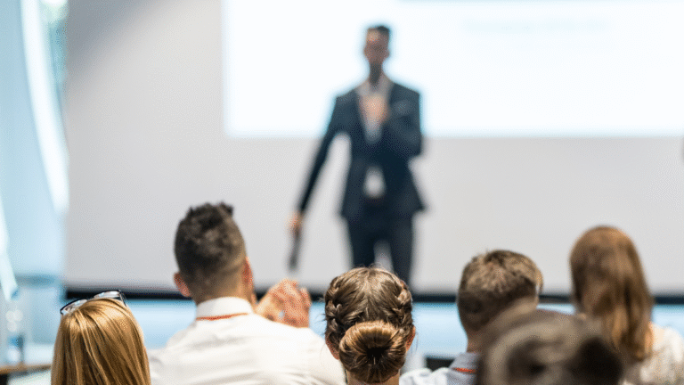 Image of a person on a stage speaking with audience