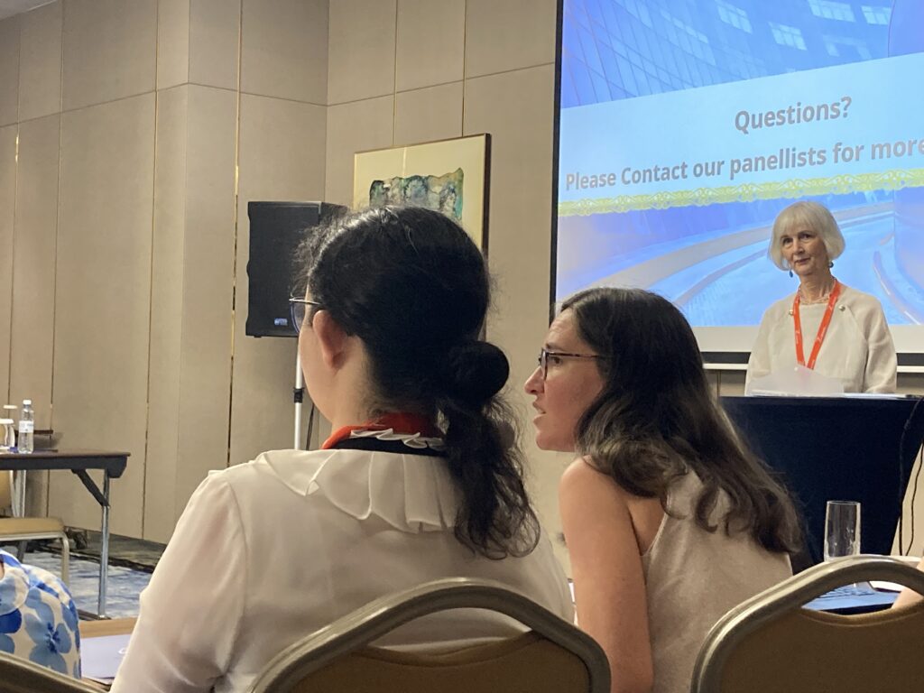 A person standing behind a podium looking at someone speaking