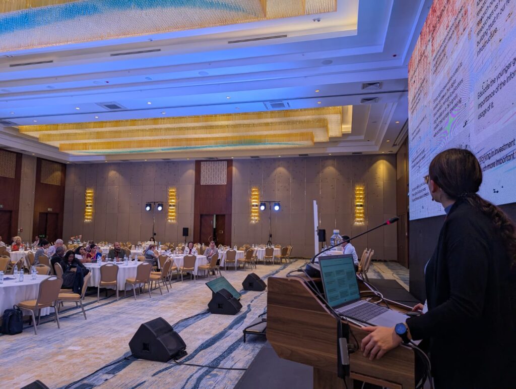 An image of a person standing behind a podium in a room with people